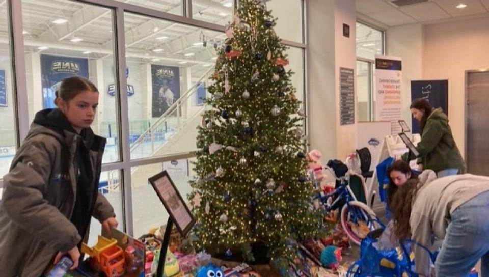 Students gather toys and gifts from the Giving Tree in the Harold Alfond Forum