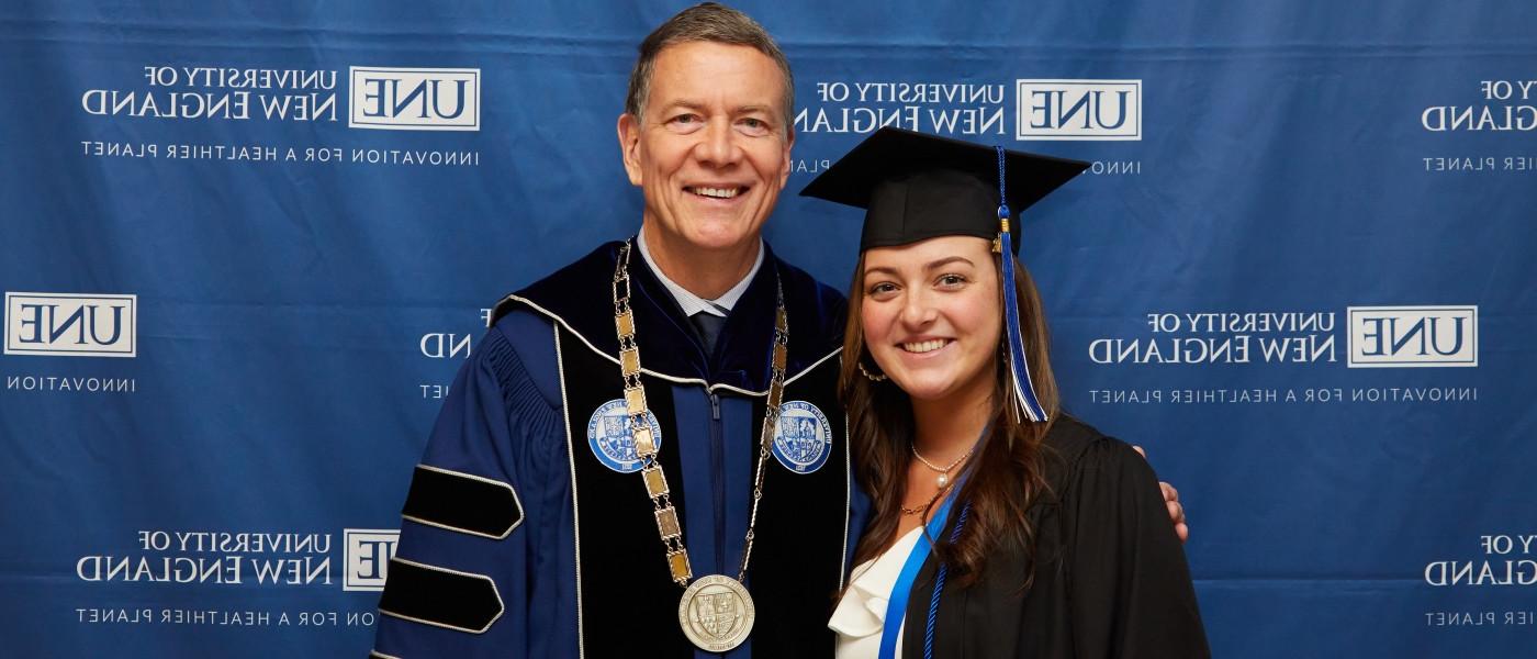 A UNE graduate poses with President James Herbert